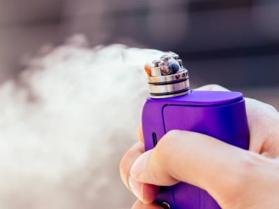 purple vape in a man's hand on a modern background.