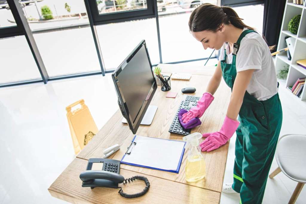 high angle view of young woman in rubber gloves cleaning office table