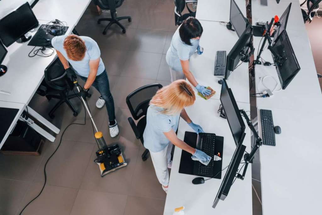 Top view. Group of workers clean modern office together at daytime.