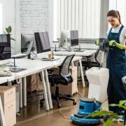 young cleaner washing floor in open space office with cleaning machine