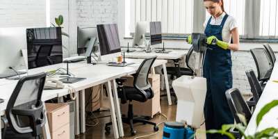 young cleaner washing floor in open space office with cleaning machine