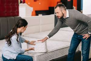 couple choosing folding mattress together in furniture store with arranged mattresses