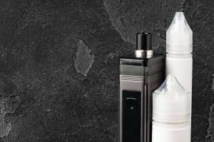 Electronic cigarette with re-fill liquid bottles on gray background close up
